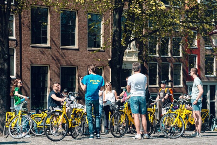 Amsterdam: Relaxed City Highlights Guided Bike Tour - Nieuwezijds Kolk Start, Yellow Bikes, and the Quick Safety Brief